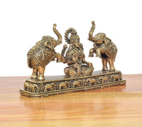 Close view of seated Lakshmi figurine between elephants with intricate base decoration.