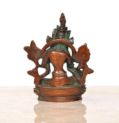 Back view of Tara Devi statue with crown and flared halo, seated on lotus base.