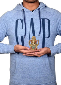 Small brass Ganesha statue held in hands, colorful blue and red enamel