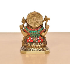 Back view brass Ganesha statue, jeweled shoulders and red skirt; detailed circular halo