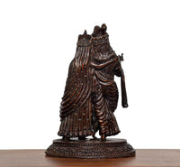 Brass Radha Krishna idol, rear/side view highlighting textured robe folds and pedestal.