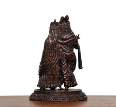 Brass Radha Krishna idol, rear/side view highlighting textured robe folds and pedestal.