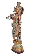 Side view of brass Lord Krishna figurine, brown with raised halo and flowing ornaments