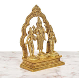Angled view of brass Vishnu with Shridevi and Bhudevi, arched frame behind the figures