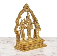 Angled view of brass Vishnu with Shridevi and Bhudevi, arched frame behind the figures