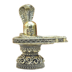 Close-up brass shivling with cobra hood above, detailed patterned base.