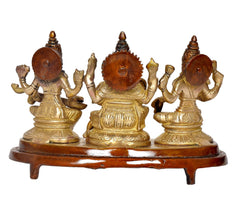 Rear view of brass-gold Lakshmi, Ganesh, Saraswati idol set on brown base