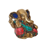 Side view brass Ganesha idol with blue eyes, turquoise necklace bands, red jeweled details