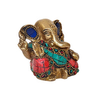 Side view brass Ganesha idol with blue eyes, turquoise necklace bands, red jeweled details