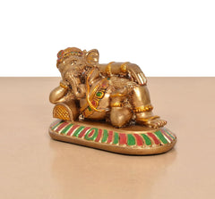 Relaxing Ganesha statue side view, gold-toned figure with patterned base and ornaments