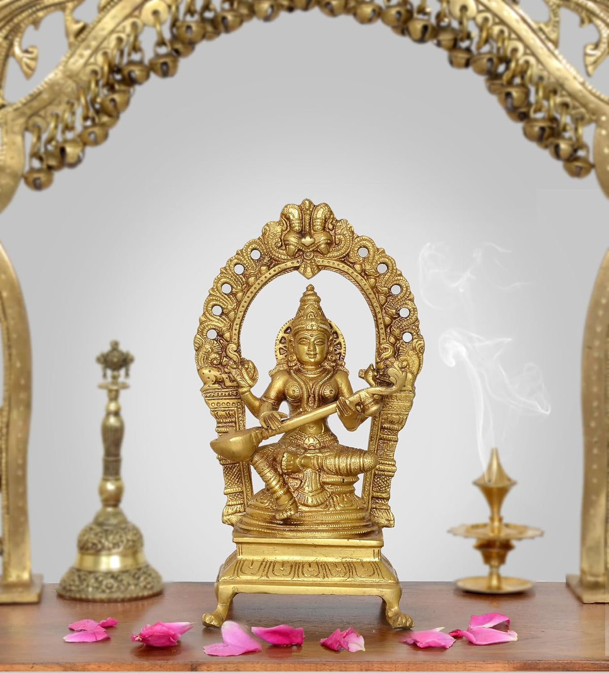 Brass Saraswati goddess idol with arched halo, four arms, ornate pedestal