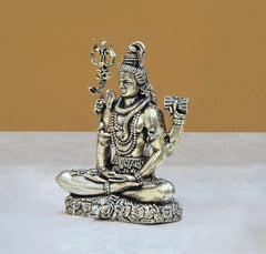 Brass Shiva seated statue with four arms, raised trident and drum, detailed