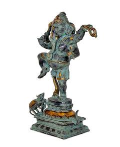 Side view of dancing Ganesha statue with turquoise body and gold accents, ornate base