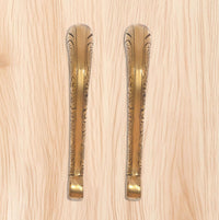 Golden brass door pull handle pair with engraved long backplates on panel.