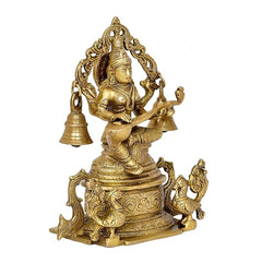 Brass Saraswati idol seated, one hand raised, ornate throne with bells