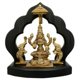 Brass Maha Lakshmi idol with elephant attendants on dark wooden temple base, 7.5 in