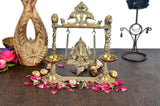 Brass Ganesha swing statue with detailed frame, chains, and two side lamp bowls
