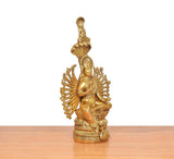 Side view of golden brass seated devi with circular spoked halo and raised hand