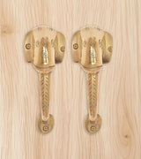 Brass Ganesha face door handle pair on light wood, two mounted levers
