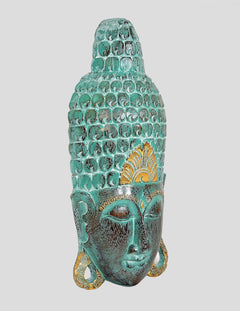 Side view of teal wooden Buddha mask wall hanging with gold accents and carved texture