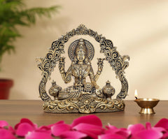 Brass Lakshmi idol with arch frame and kalash pots, seated on ornate base