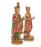 Resin swami figures in three-quarter view, holding hand gestures, crowns, robes, floral base