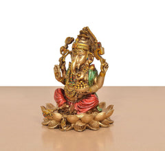 Ganesh resin statue seated on lotus with raised hands, gold ornaments and red wrap