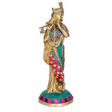 Brass Krishna idol side view, ornate jewelry, teal sash and red circular motifs