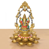 Brass Ganesh diya idol with arched frame, 21 brass oil lamp bowls around pedestal