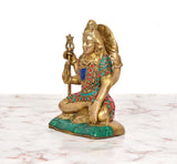 Side view of Lord Shiva brass statue seated with trident, jeweled multicolor attire