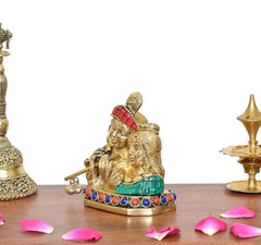 Brass Radha Krishna statue, close side view; teal sash, red crown, bead border