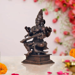 Saraswati statue side view, seated with veena across lap, dark copper bronze tone