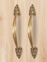 Golden brass door pull pair, long curved handles with engraved leaf motifs