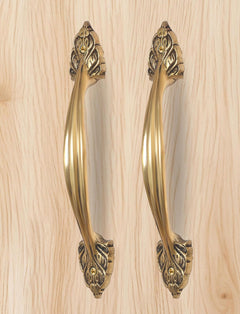 Golden brass door pull pair, long curved handles with engraved leaf motifs