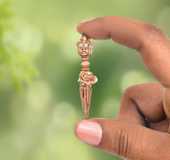 Brass furba phurpa with carved deity head and pointed tip, held in fingers