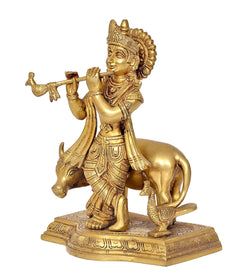 Brass Lord Krishna with flute, riding a cow, ornate base with engraved patterns