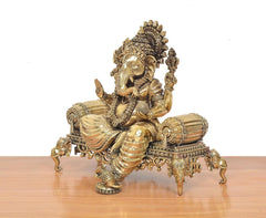 Brass Ganesha idol side view, seated pose on ornate singhasan platform