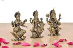 Brass Lakshmi, Saraswati and Ganesha idols with ornate crowns, seated on lotuses.