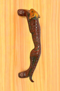 Jaguar-shaped brass door handle on door with orange head detail and curved metal grip