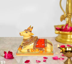 Resin Nandi cow idol, yellow with red saddle and gold details on base
