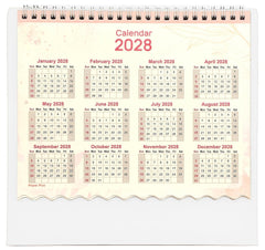 Spiral desk calendar showing 2028 monthly grid, off-white base with scalloped bottom