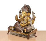 Brass Ganesha statue in side view, seated on patterned base with drum-like accessory