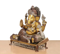 Brass Ganesha statue in side view, seated on patterned base with drum-like accessory