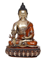 Seated Buddha figurine with brass face and orange robe, holding flower staff