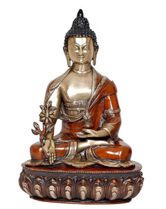 Seated Buddha figurine with brass face and orange robe, holding flower staff