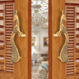 Brass peacock design door handle pair on a wooden door, golden finish