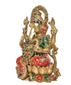 Brass Ganesha idol in profile, red skirt, green-blue patterns, decorative arms and halo