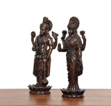 Side view of standing brass Lakshmi and Vishnu idols with detailed jewelry and drapery