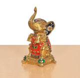 Brass elephant figurine, seated pose with raised trunk; multicolor painted details