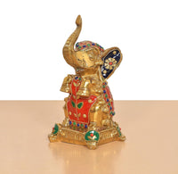 Brass elephant figurine, seated pose with raised trunk; multicolor painted details